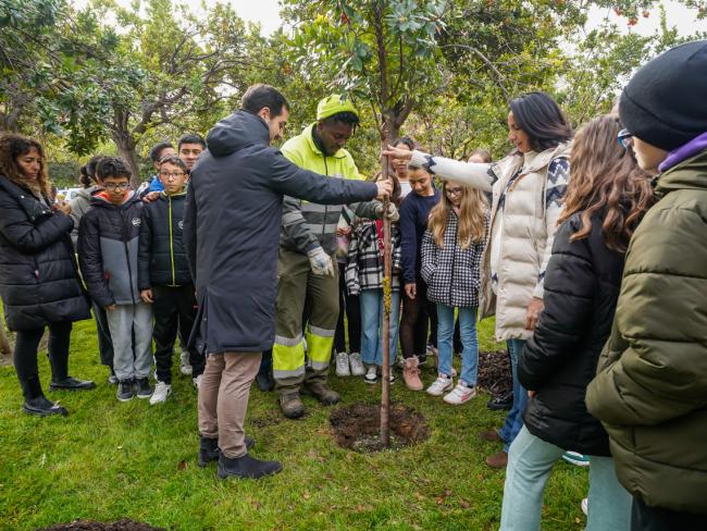 El alcalde, Alejandro Navarro Prieto, la concejala de Medio Ambiente, Esperanza Fernández, y alumnos del CEIP Buen Gobernador plantado el madroño 45 del Parque Constitución