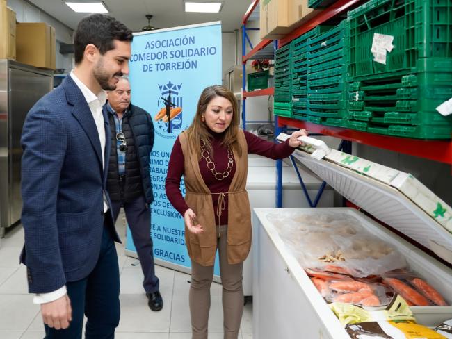 Margarita Villa mostrando al alcalde algunos de los alimentos almacenados